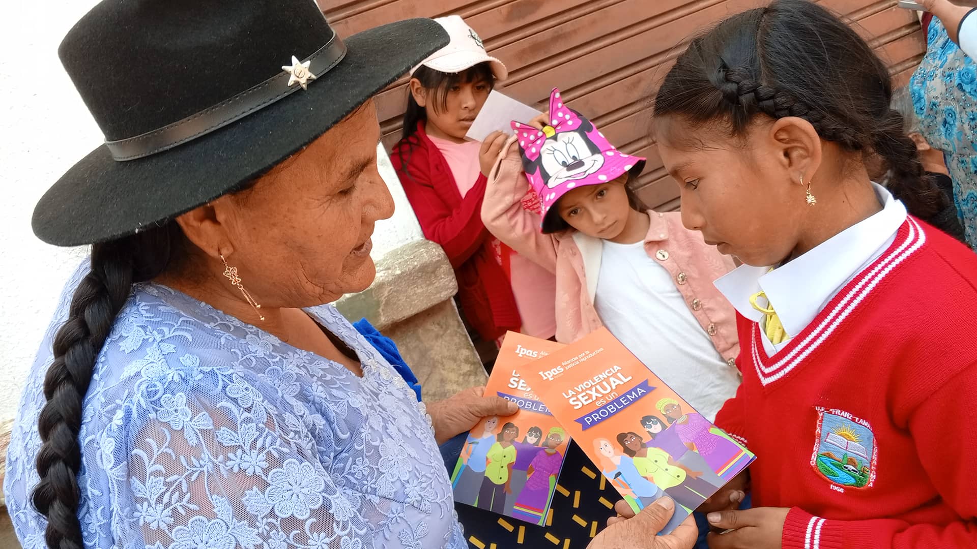 Mujer boliviana brindando información a niña y material sobre la prevención de la violencia sexual y de género Mujer boliviana brindando información a niña y material sobre la prevención de la violencia sexual y de género