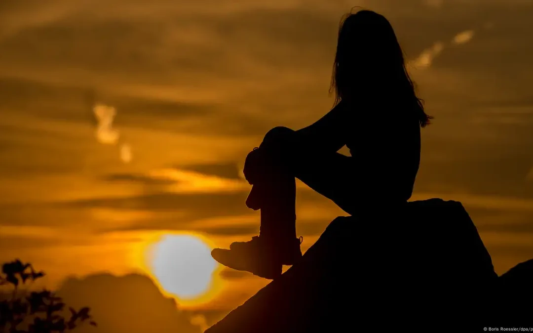Girl on a rock looking at sunset