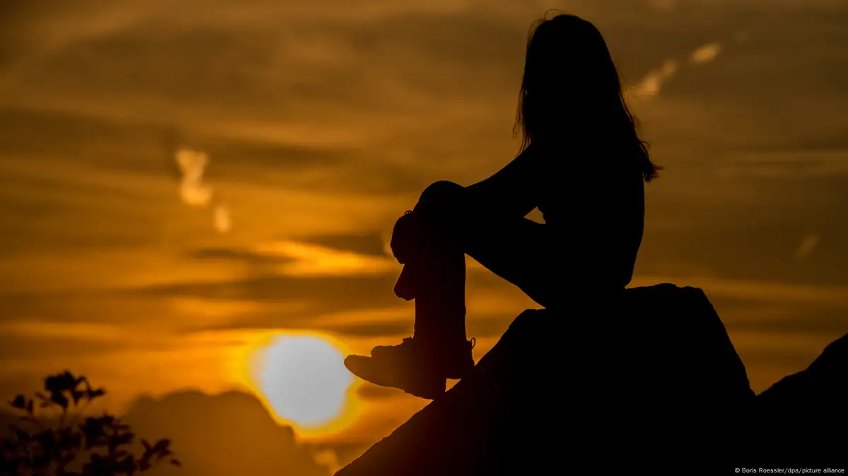 Girl on a rock looking at sunset